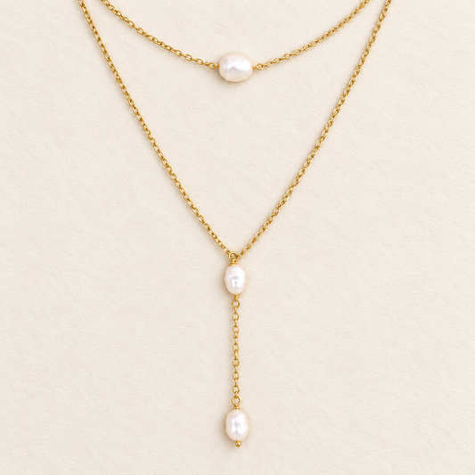 Pearl choker and lariat necklace set in 18k gold filled, both necklaces laid flat on a cream background